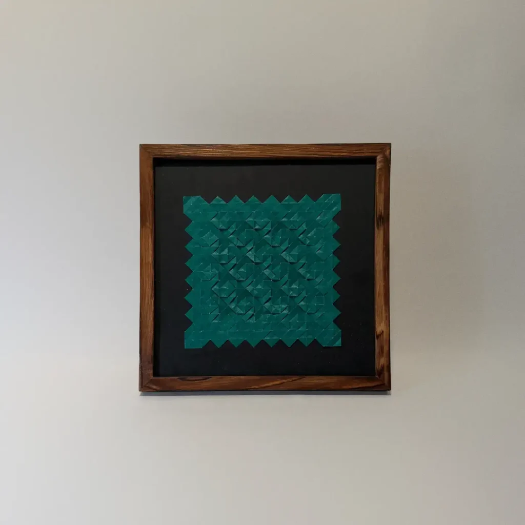 green paper origami tessellation artwork with black matting in a wooden frame