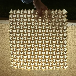 origami tessellation for puffed square cross pattern held in front of a light